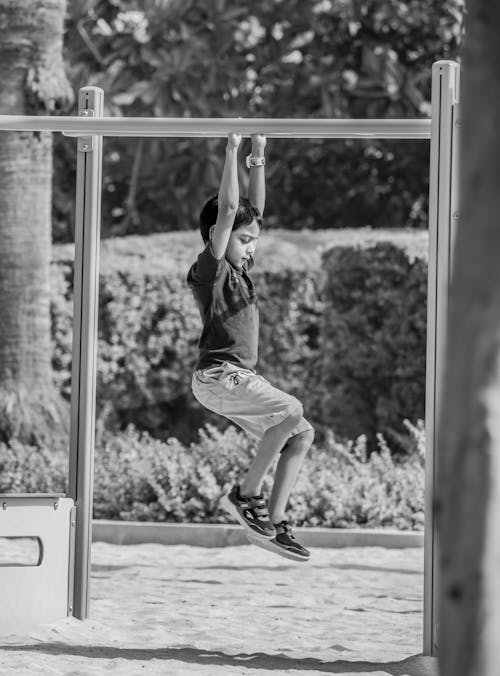 Boy Holding on Monkey Ladder in Playground