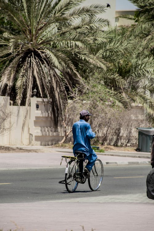 Man Riding Bike on Street in Town