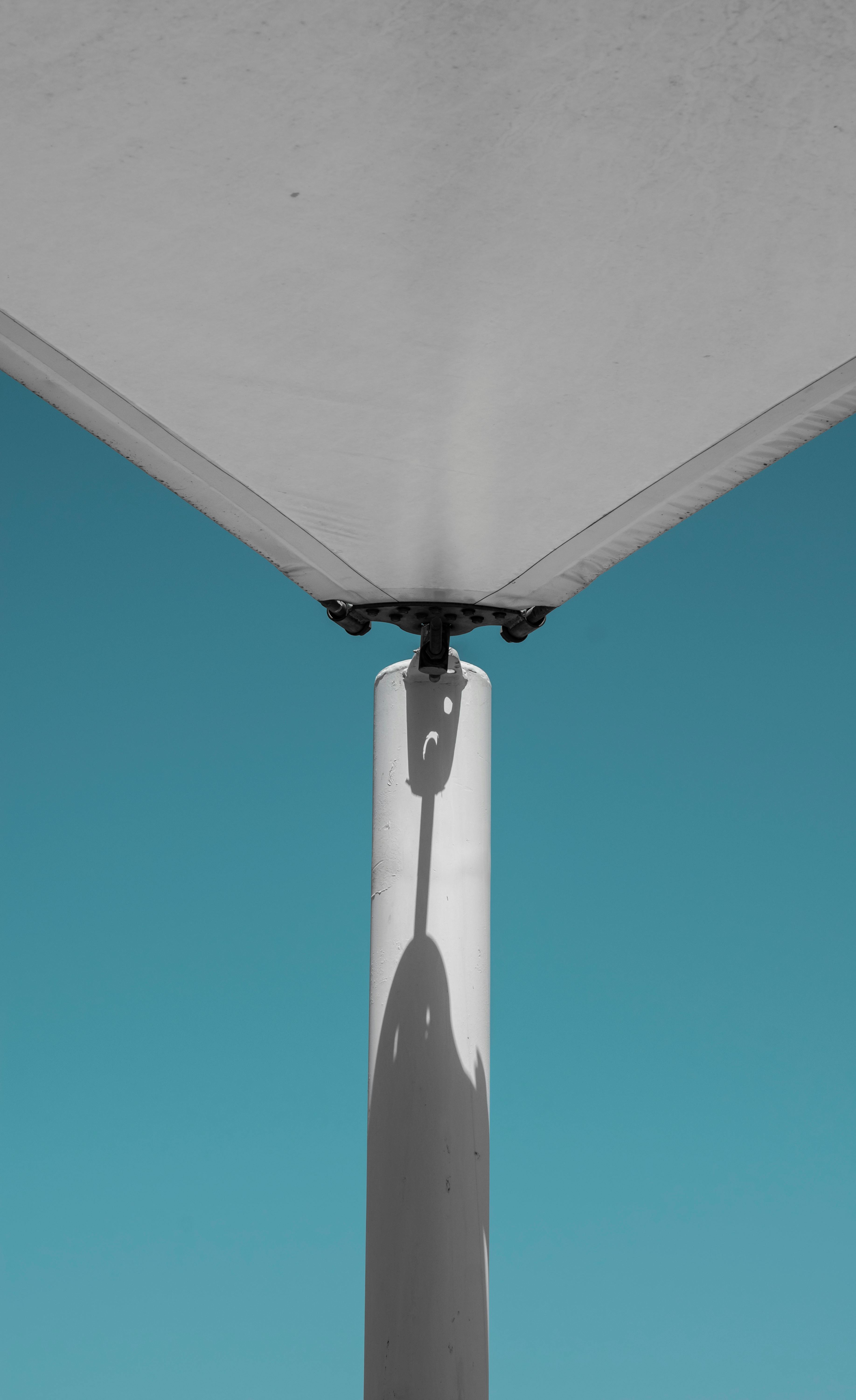 A vertical shot of a modern canopy post casting a shadow against a clear blue sky in Dubai.