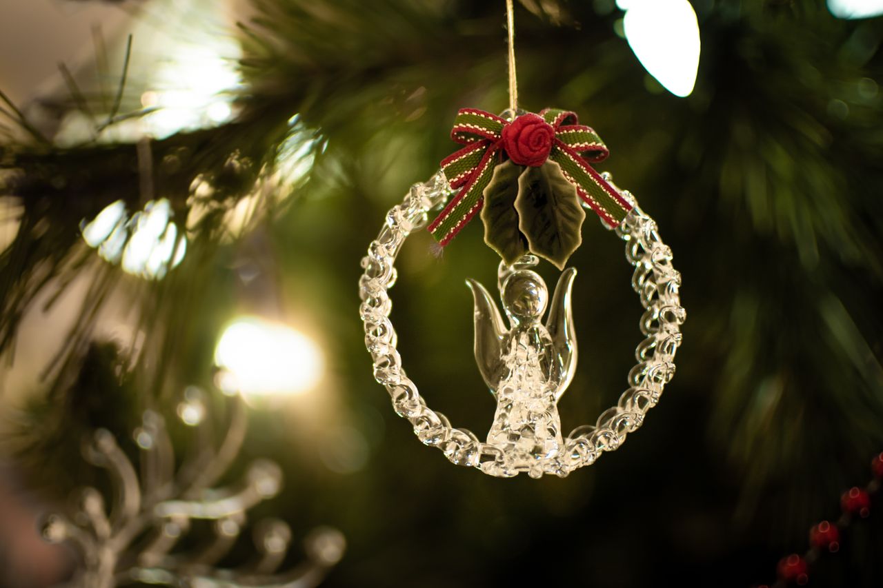 a delicate glass angel ornament with a red ribbon adorns a festive chr