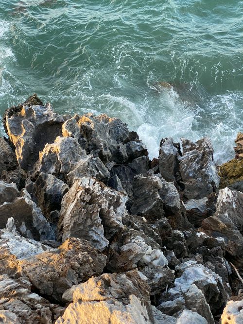 Free Capture of rugged rocks and vibrant waves along the seashore. Stock Photo