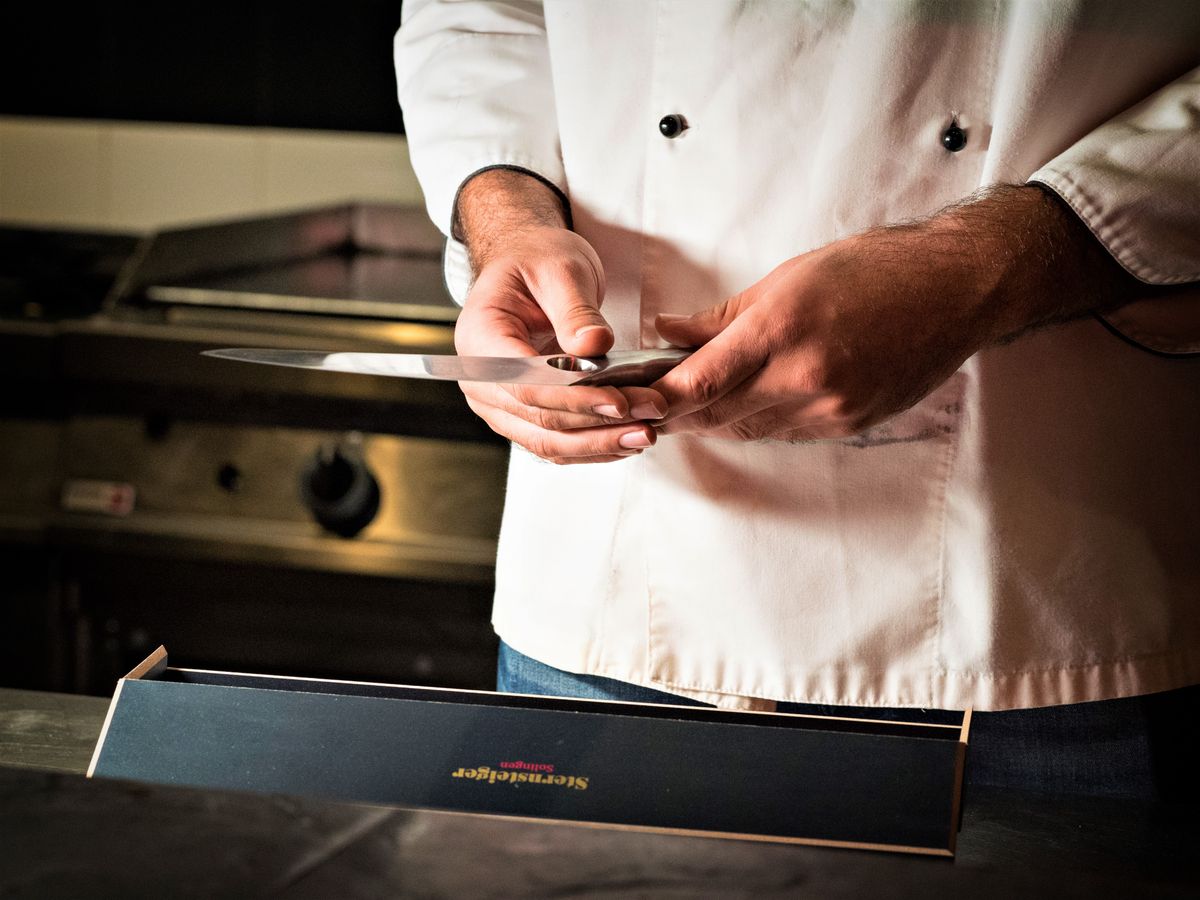 Proper grip matters as much as carrying technique Close-up of a chef's hands holding a sharp kitchen knife