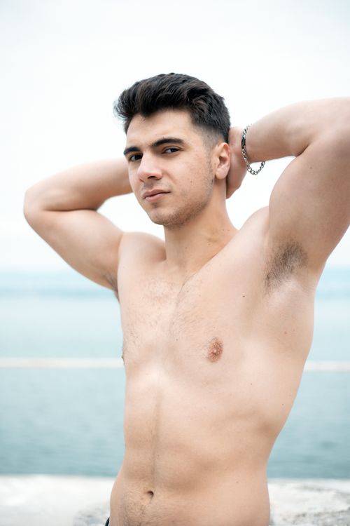 Free Young, muscular man posing shirtless by the sea, showcasing fitness and confidence. Stock Photo
