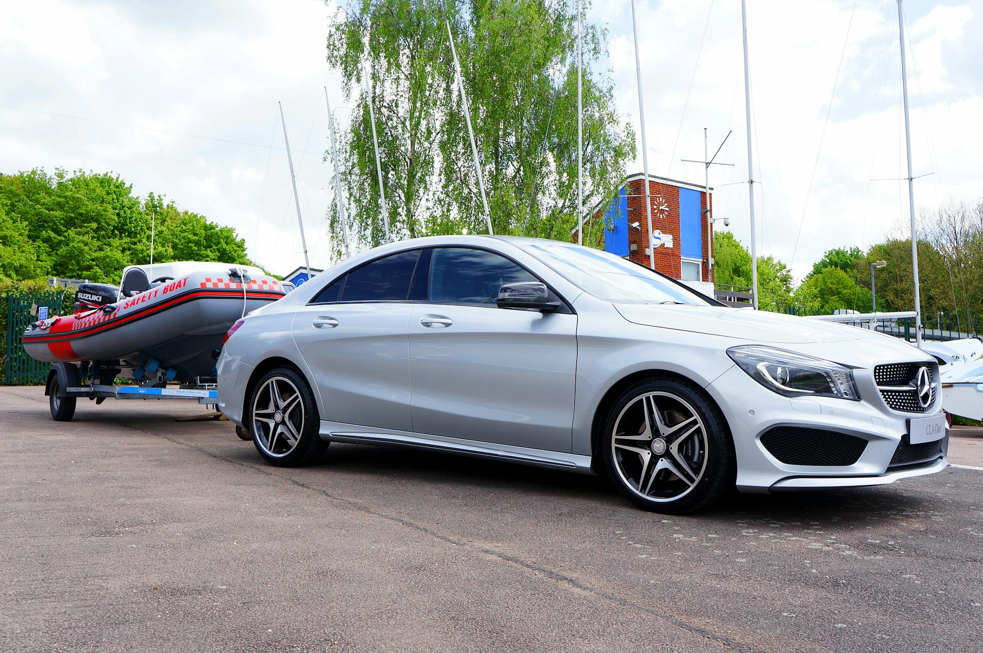 Silver luxury car towing a safety boat at a marina, showcasing elegance and outdoor adventure.
