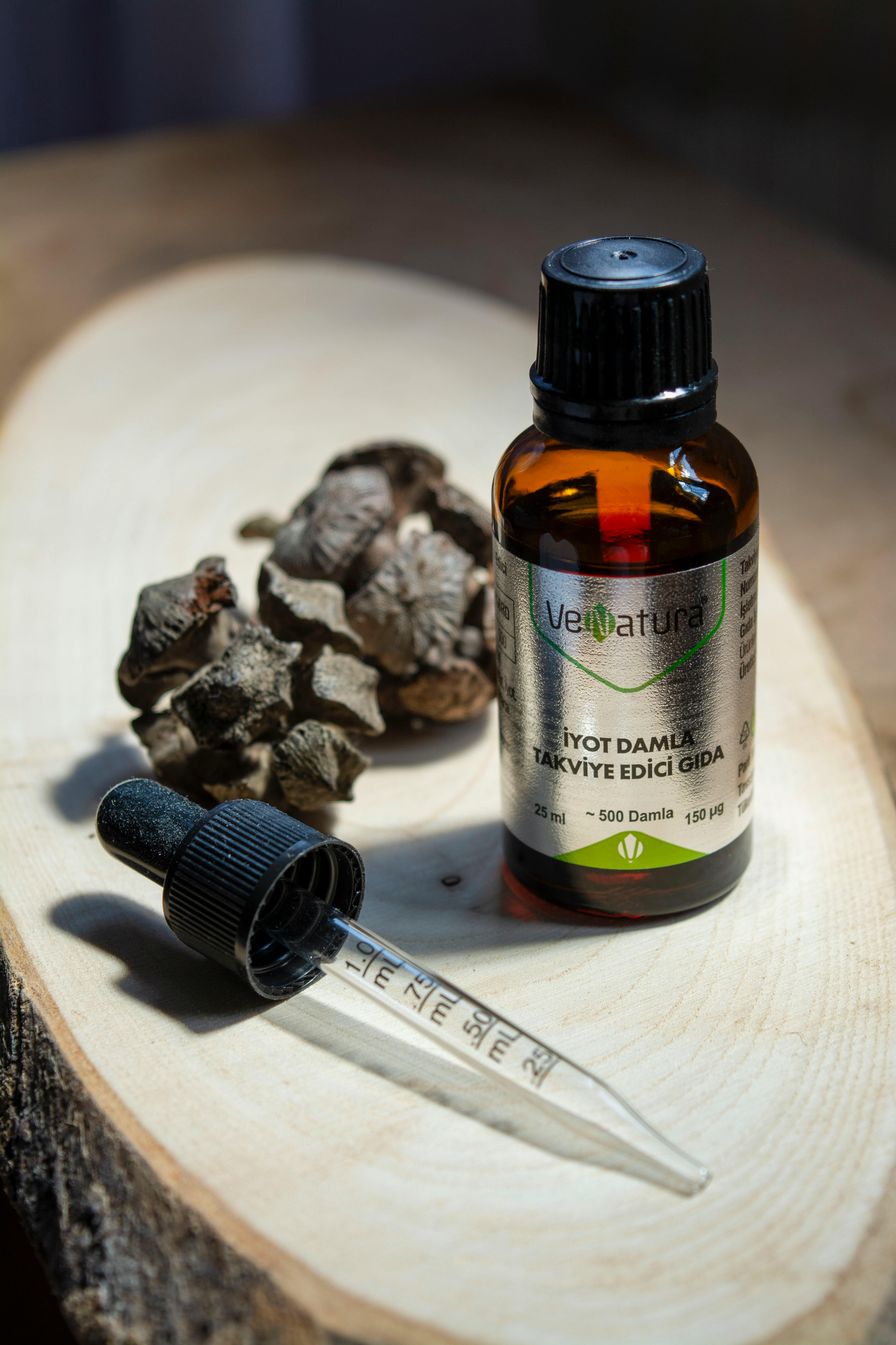 Close-up of an organic herbal oil bottle with a pipette on a wooden surface, natural lighting.