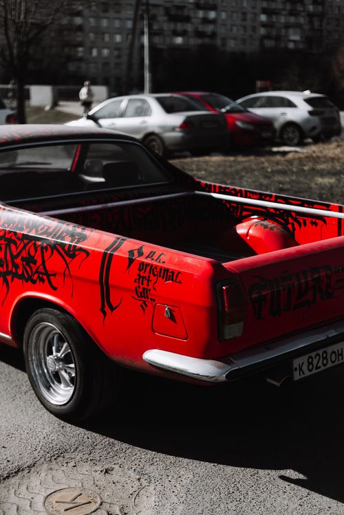 Free Vintage red pickup truck with unique graffiti parked in urban area, showcasing custom retro style. Stock Photo