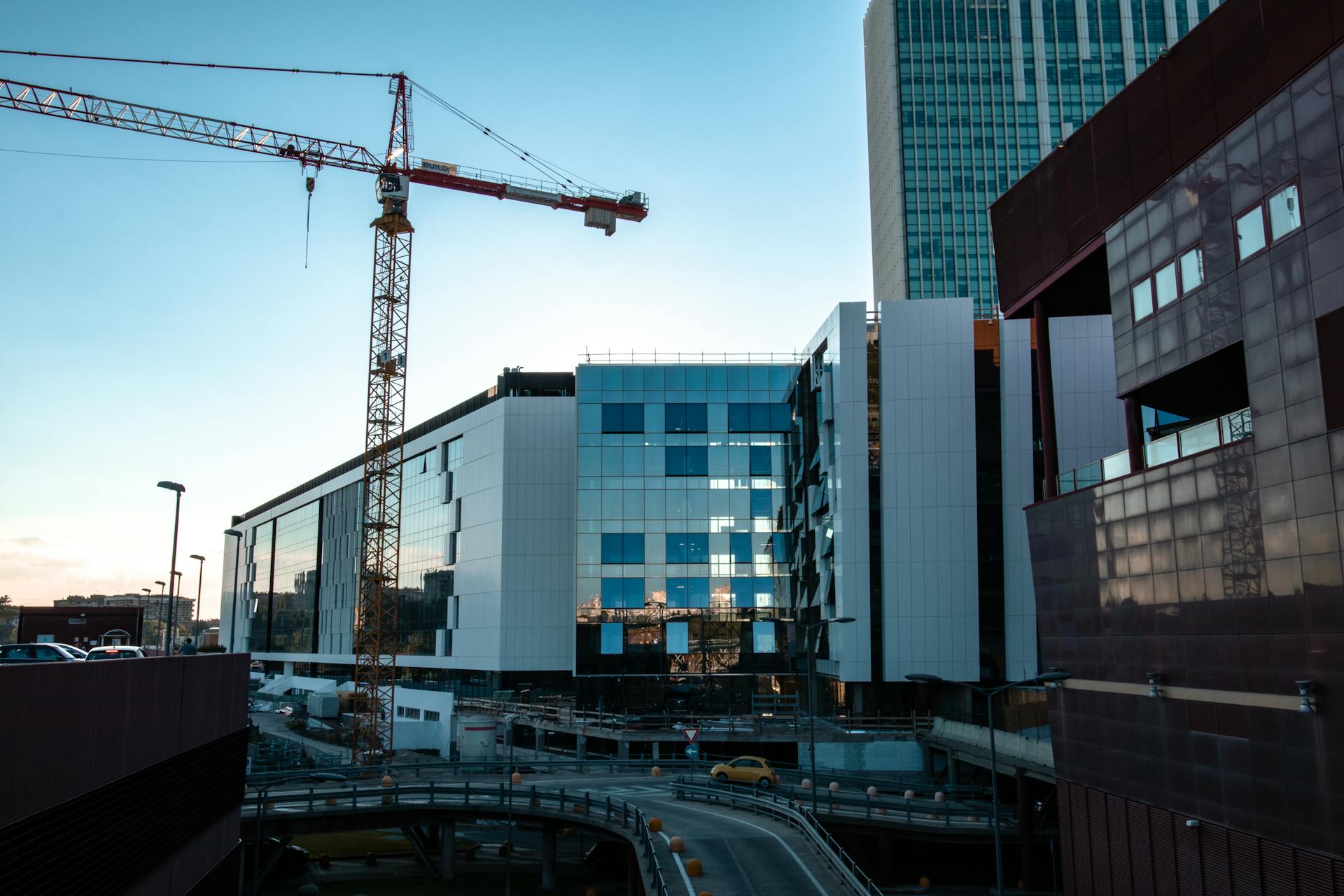 Contemporary building under construction with cranes, showcasing urban architecture and development.