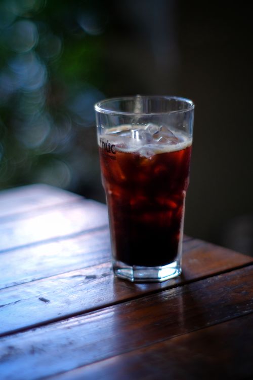 Free A refreshing iced drink in a glass, placed on a wooden table with a blurred background. Stock Photo