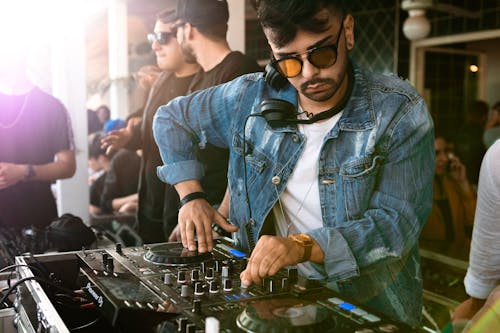 Homem Vestindo Jaqueta Jeans Azul Enquanto Usa O Controle Dj Preto