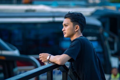 Free A young man leans on a railing, contemplating in an urban environment. Stock Photo