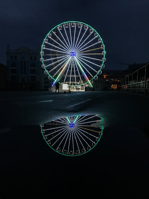 Lit up Ferris Wheel Reflecting in Water