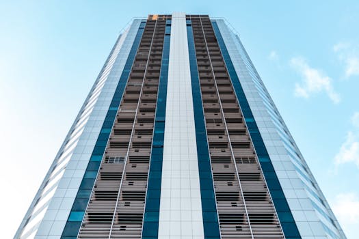 从低角度仰望现代摩天大楼，玻璃板映衬着清澈的蓝天