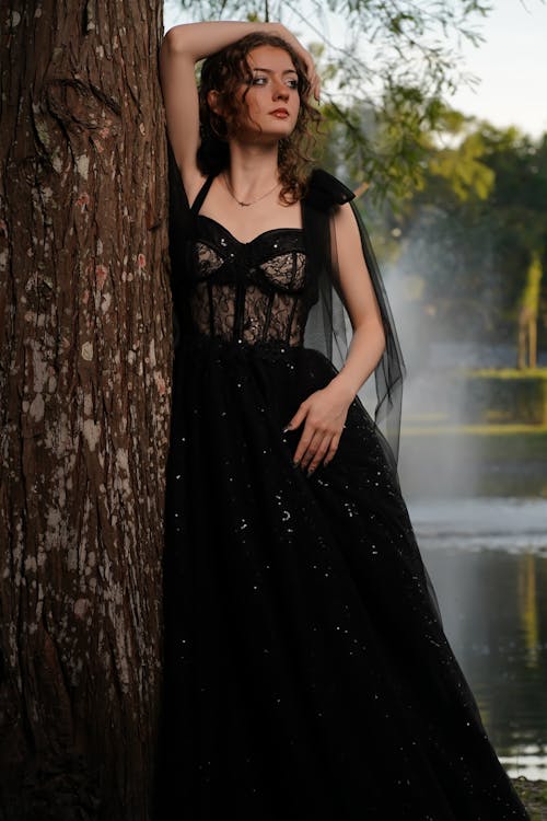 Young Woman in a Black Dress Posing in a Park 