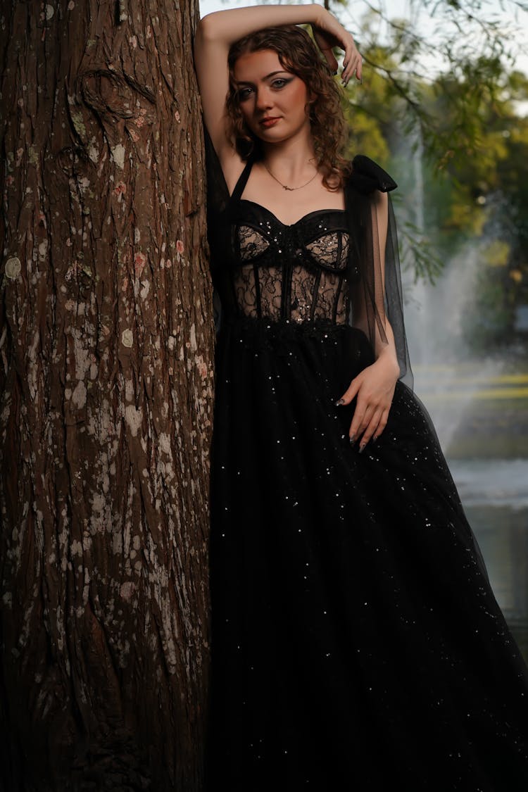 Woman In Black Gown Leaning Against Tree