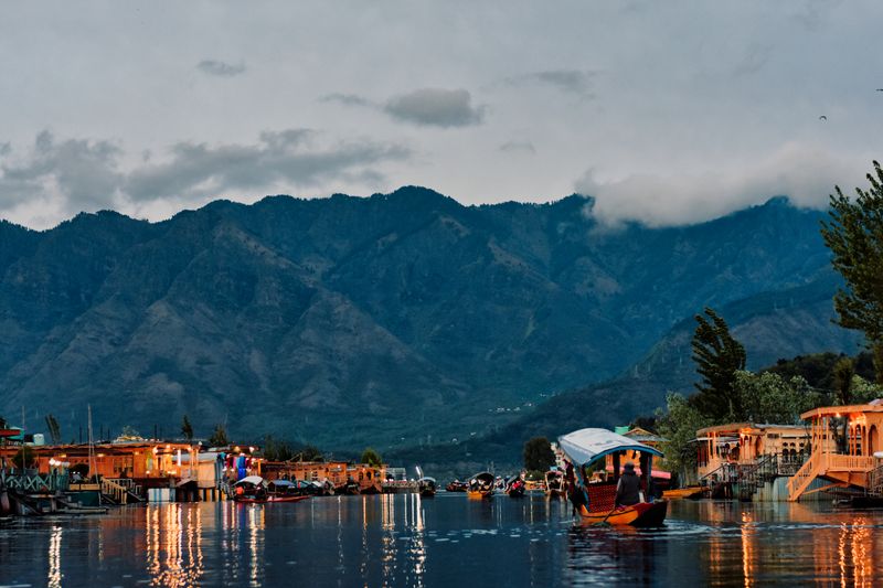 A peaceful view of Dal Lake in Srinagar with colorful boats against the backdrop of majestic mountains