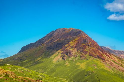 Free A vibrant mountain landscape with lush green slopes beneath a clear blue sky. Stock Photo
