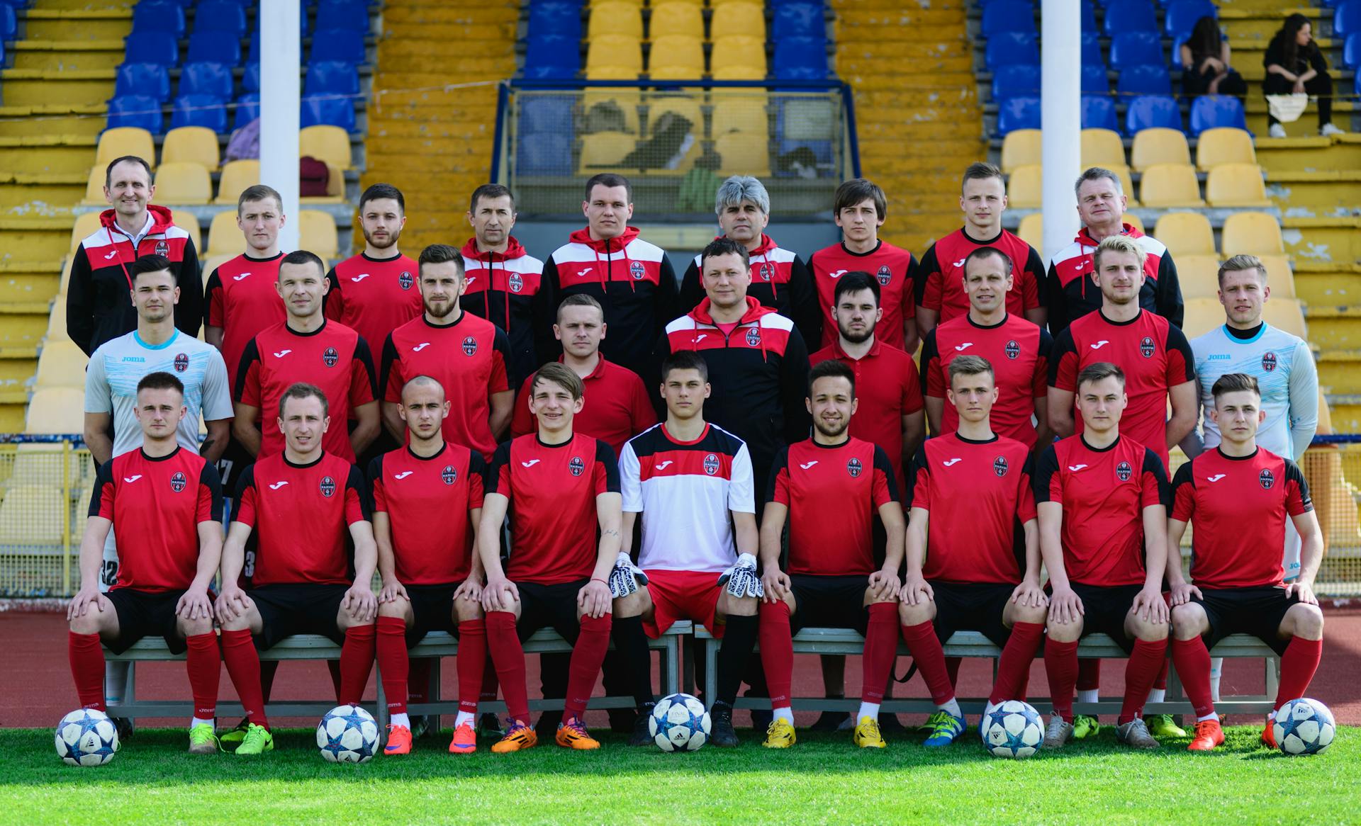 Group photo of a professional soccer team posing in a stadium, showcasing sportswear and teamwork.