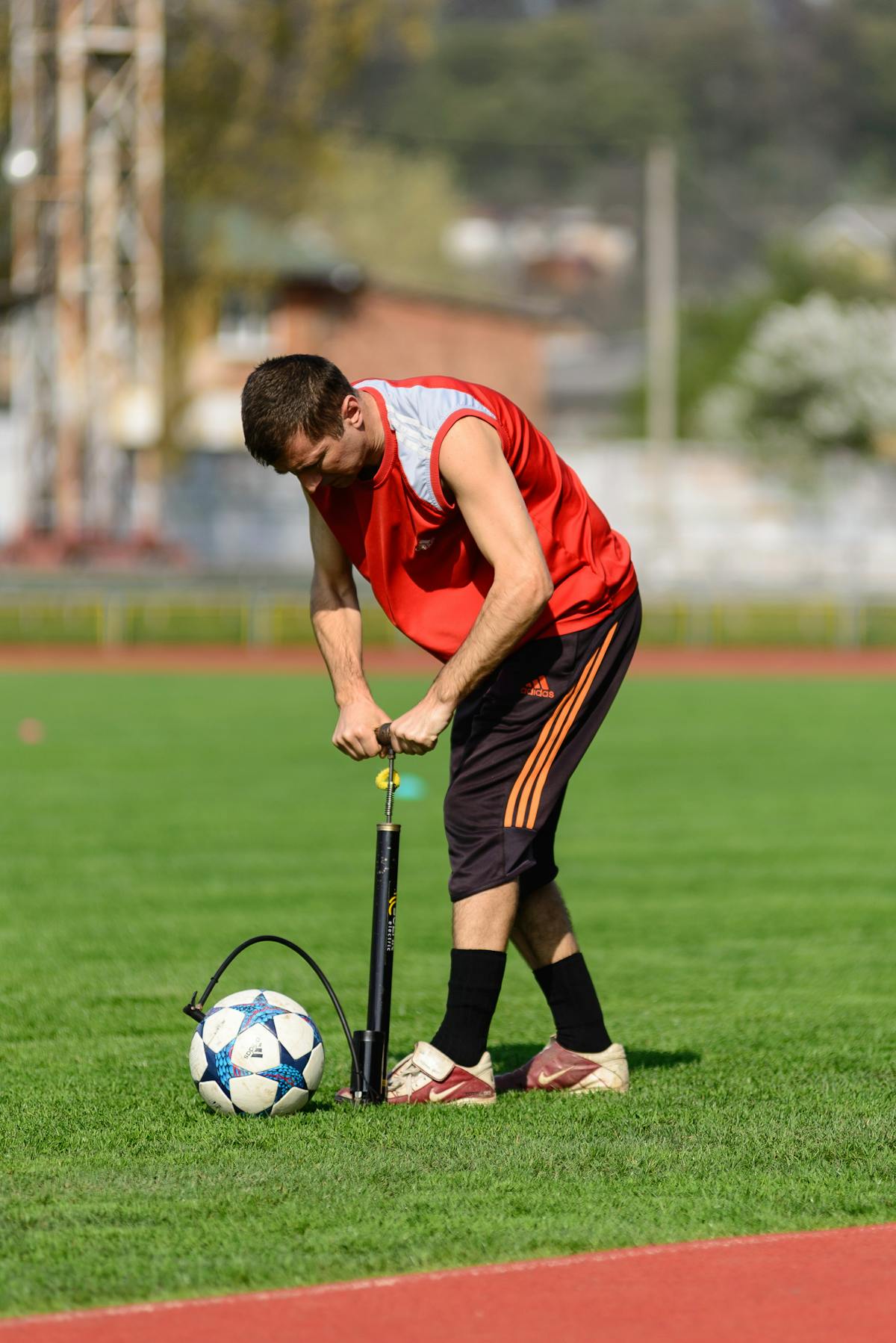 Uomo che gonfia un pallone da calcio usando una pompa con manometro