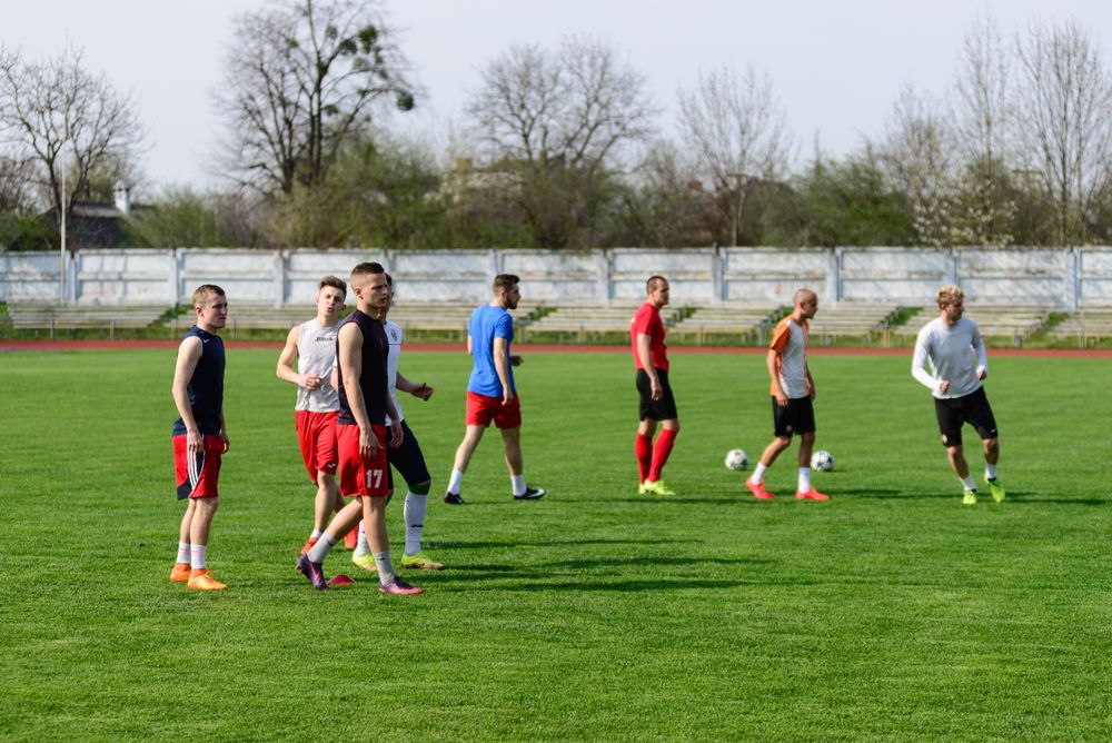 Group of football players wearing mixed training tops and shorts on a practice field