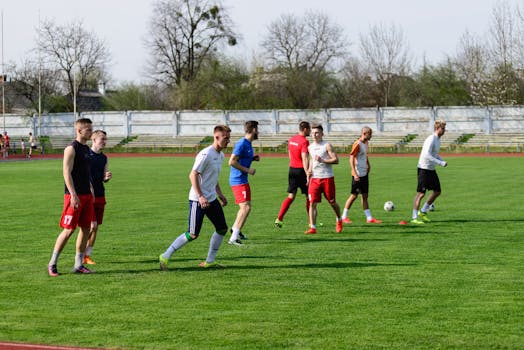 A group of young male athletes practicing soccer on an outdoor field on a sunny day.
