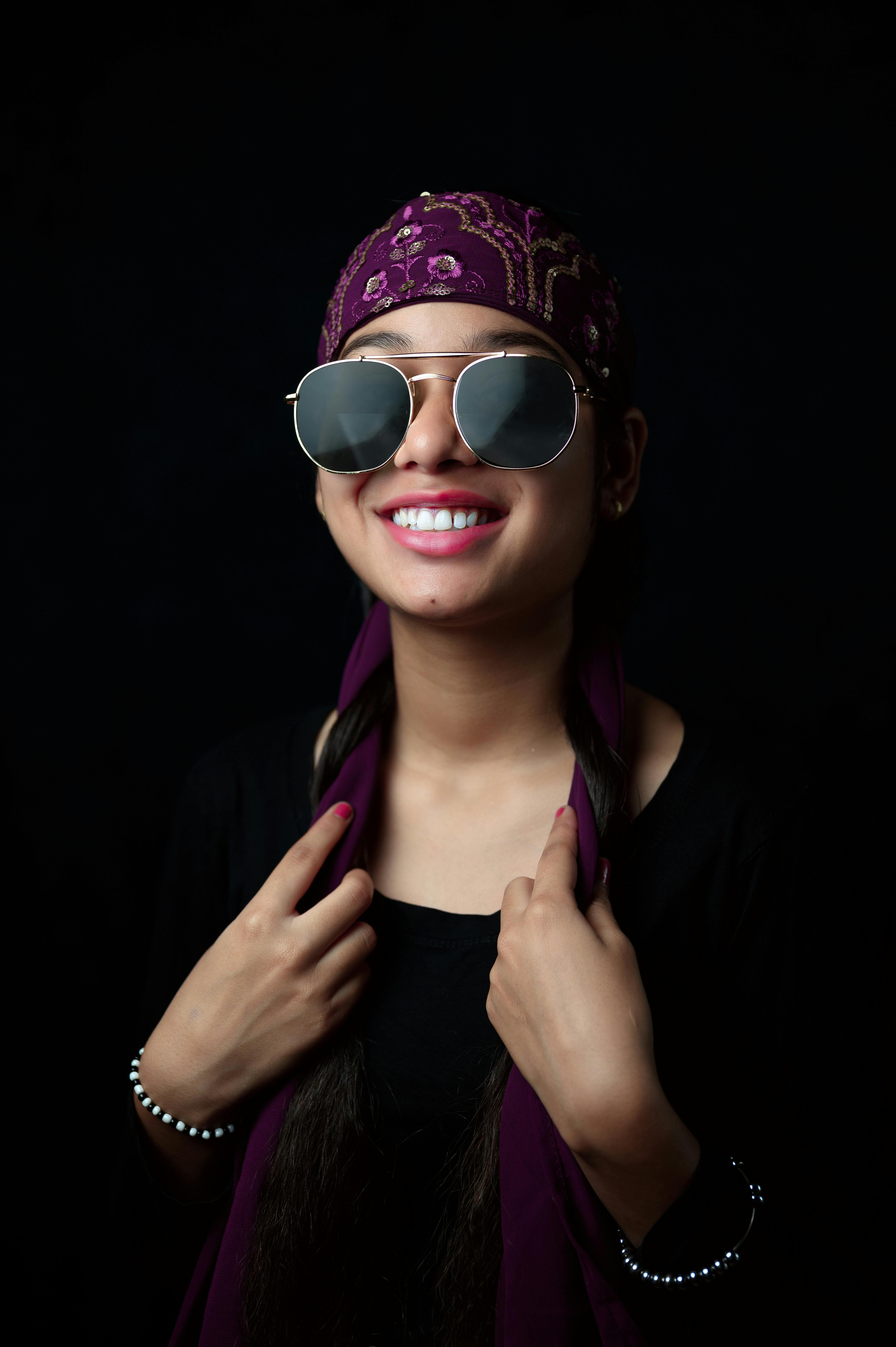 Portrait of a stylish young woman in sunglasses and bandana with a big smile.
