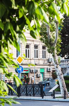 Street view of an urban area with a historic building and lush greenery in focus.