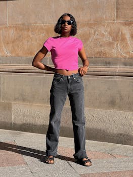 Portrait of a stylish black woman in pink top and jeans standing on a street in Glasgow, Scotland.