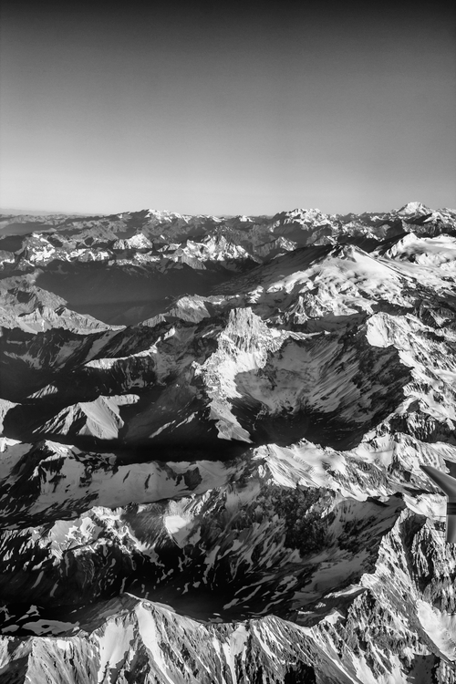 Free Dramatic aerial view of a vast mountain range covered in snow and shadow. Stock Photo
