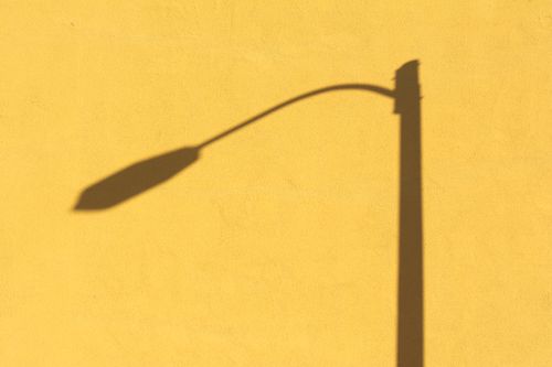 Free Artistic shadow of a streetlamp on a bright yellow wall, showcasing contrast and minimalism. Stock Photo