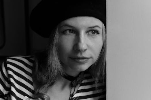 一位戴着贝雷帽和条纹衬衫的女子，在引人注目的黑白特写肖像中看起来若有所思