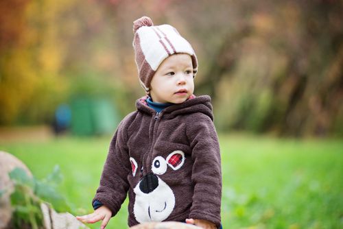 Free A cute toddler wearing a bear jacket and beanie playing outside on a bright autumn day. Stock Photo