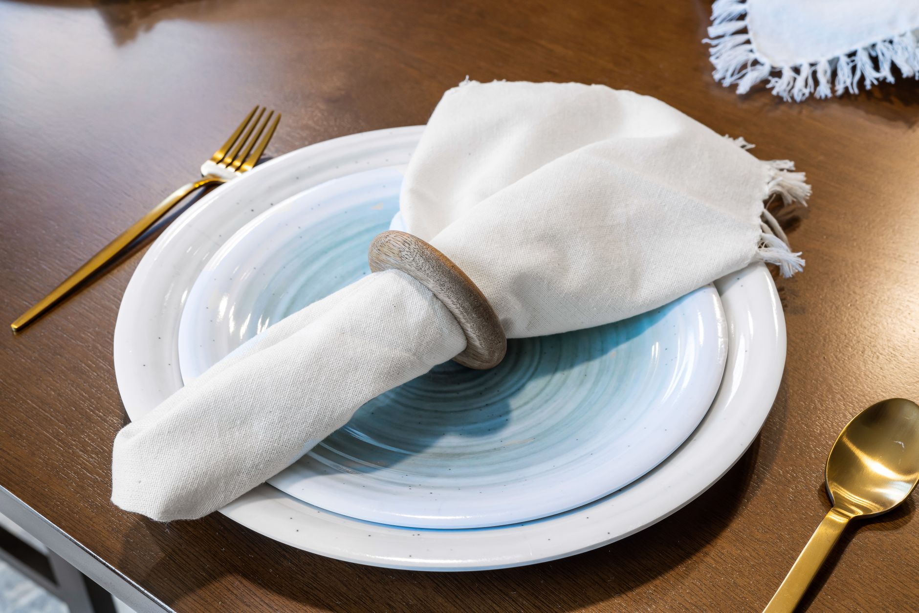Stylish table setting featuring white ceramic plates, gold cutlery, and linen napkin for a sophisticated dining experience.