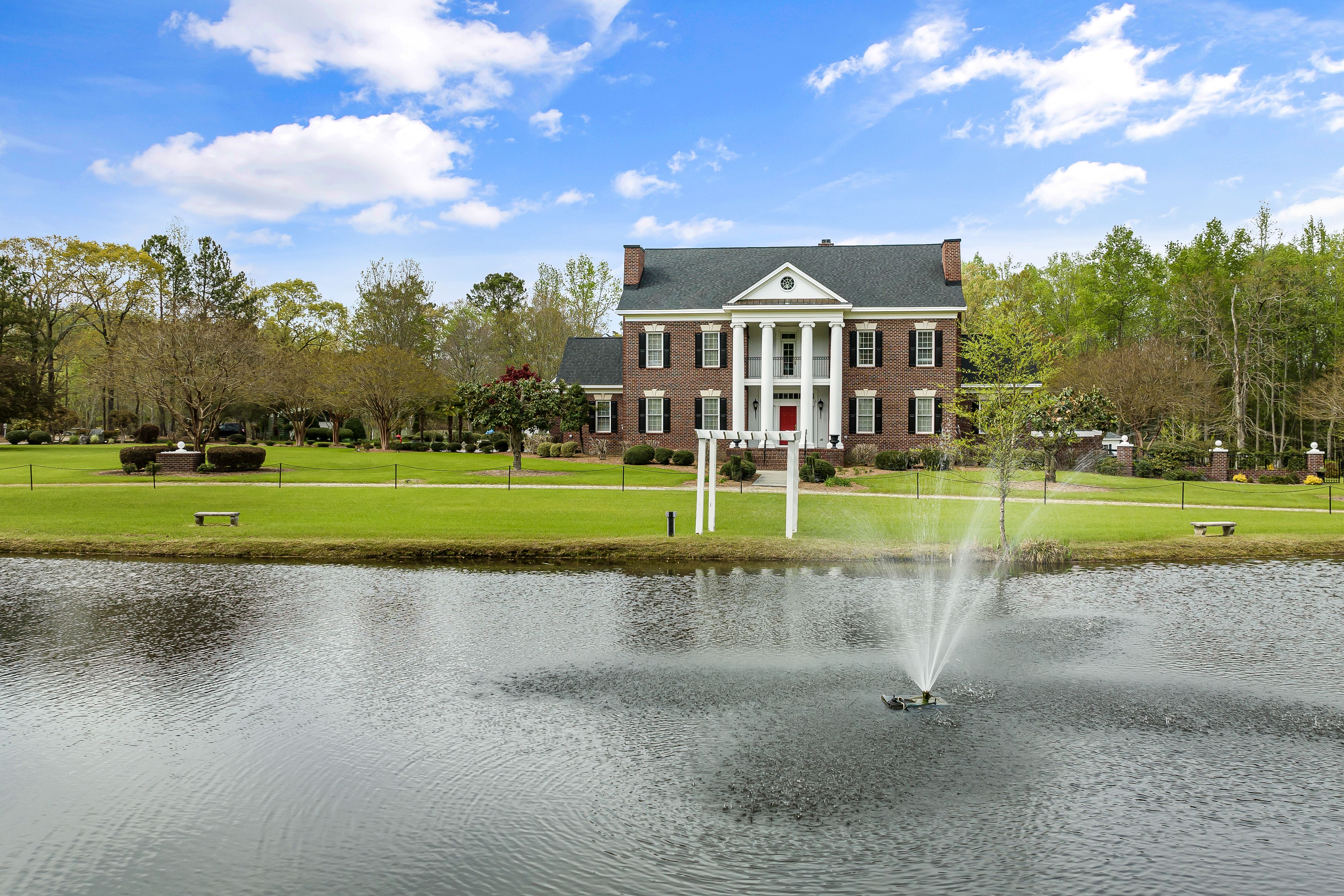 Stunning brick mansion with a fountain and scenic pond view in Sims, North Carolina.