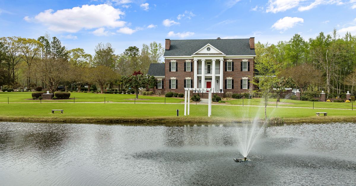 Stunning brick mansion with a fountain and scenic pond view in Sims, North Carolina.