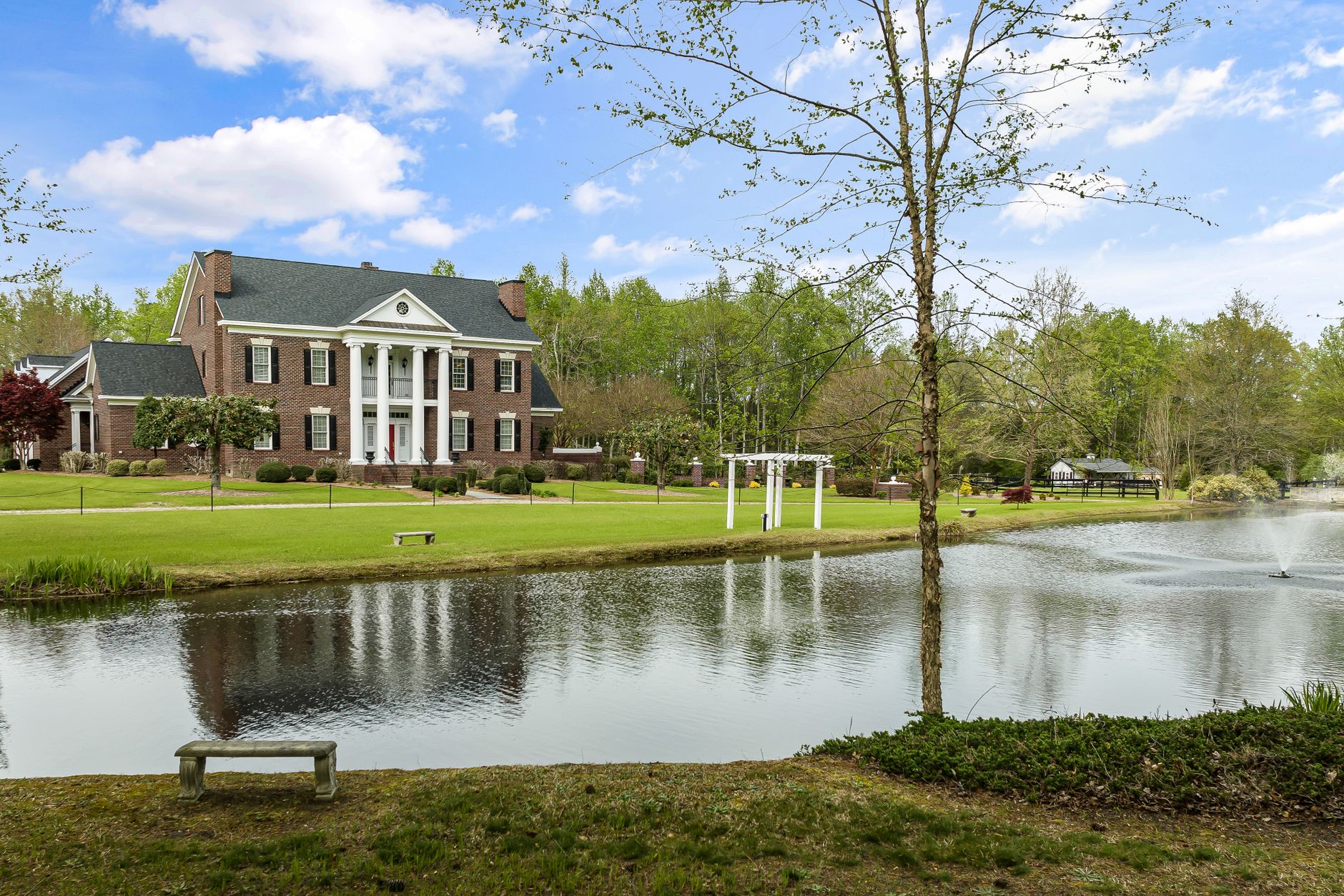 Beautiful colonial-style house with a pond in Sims, NC, showcasing classic architecture and serene surroundings.