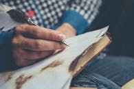 特写：一个人用羽毛笔在老式笔记本上写字