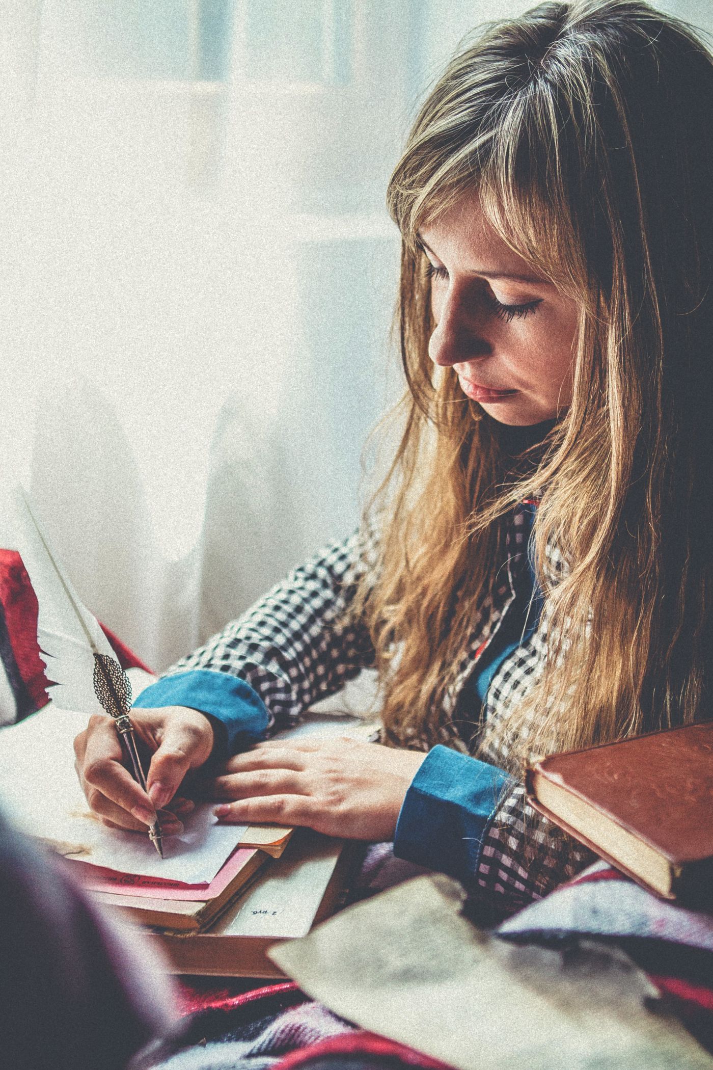 امرأة تكتب بمذكرة قرب النافذة بتأمل