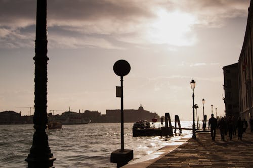 Silhouetted Buildings and Pedestrians on a Walkway by the Canal in Venice, Italy 