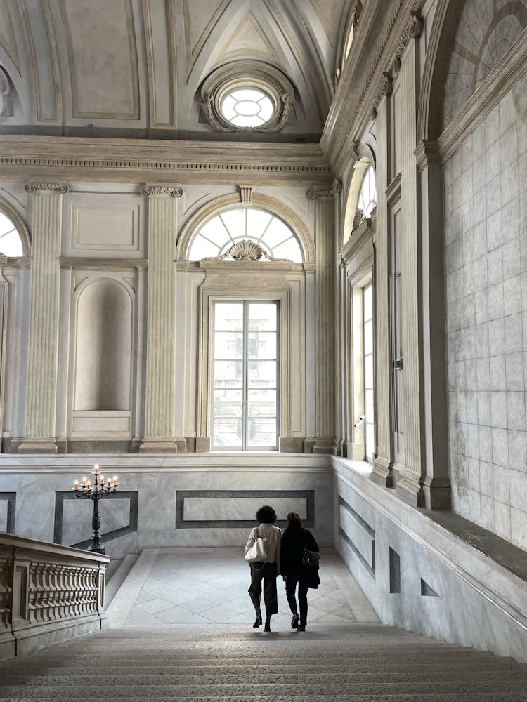 Two Women Walking Down The Stairs In A Museum 