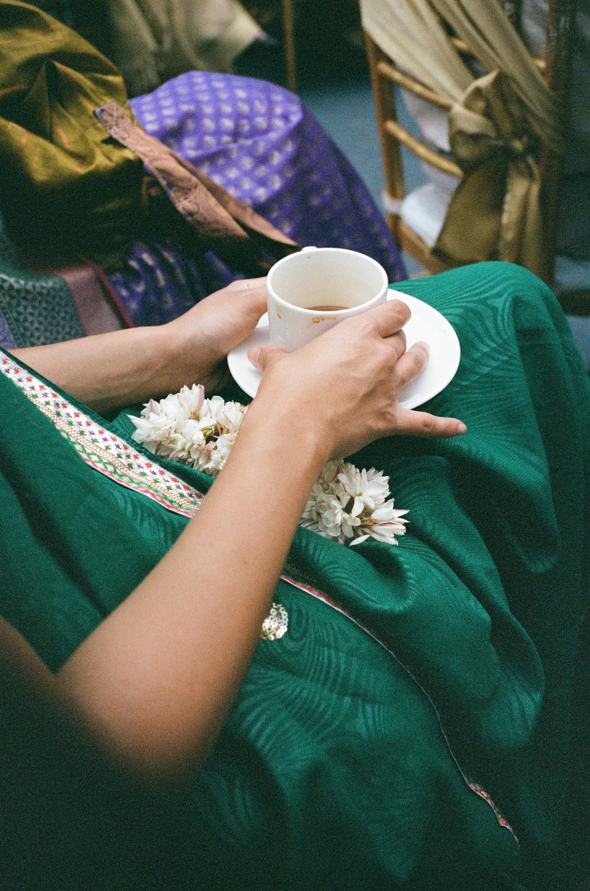 Close-up of a woman seated with coffee in Bengaluru, India, wearing a green dress adorned with white flowers.