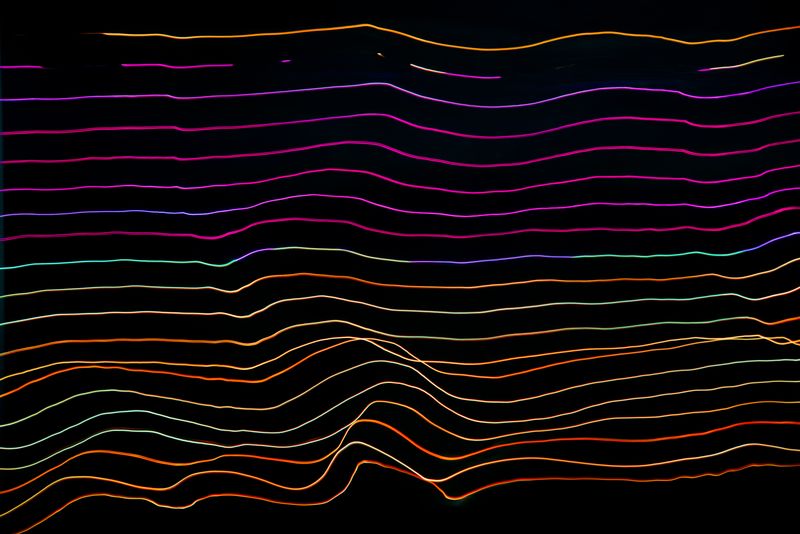 Colorful abstract light trails fanning outward across a dark background