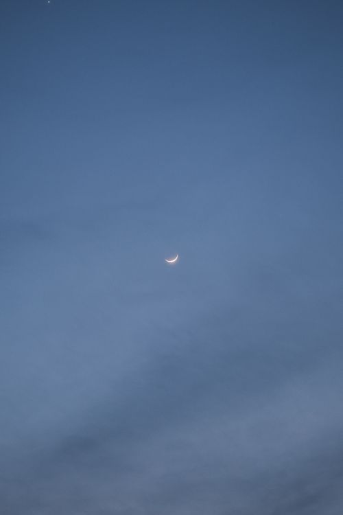 Free A serene crescent moon against a clear evening sky, highlighting twilight beauty. Stock Photo