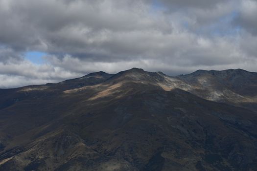 Explore the dramatic mountain range under an overcast sky, showcasing natural beauty and rugged terrain.