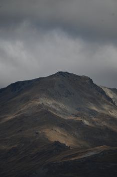 A moody mountain peak under dramatic cloudy skies showcasing nature's raw beauty.