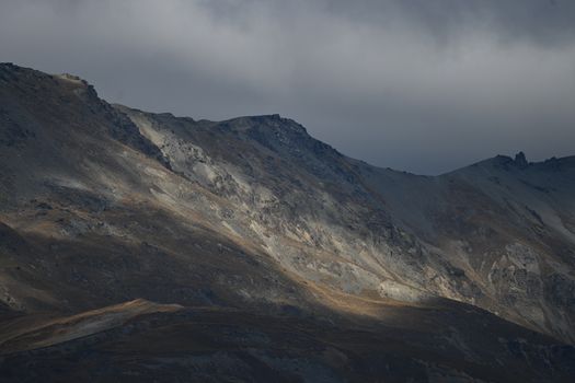 A stunning mountainous landscape under a dramatic overcast sky, capturing nature's raw beauty.