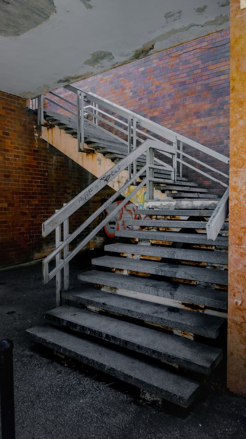 Free Moody interior of an abandoned building featuring a stairway with graffiti. Stock Photo