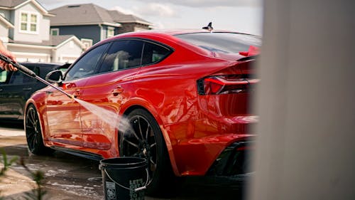 Red Car Being Washed in a Residential District