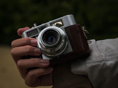 Free A close-up shot of a hand holding a vintage camera with visible lens details. Stock Photo