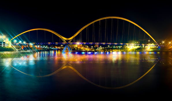 一座明亮的现代吊桥在夜间呈现出令人惊叹的景象，水面上倒映着缤纷的色彩