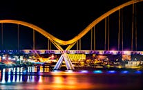 现代拱桥的夜景令人惊叹，城市灯光倒映在水面上